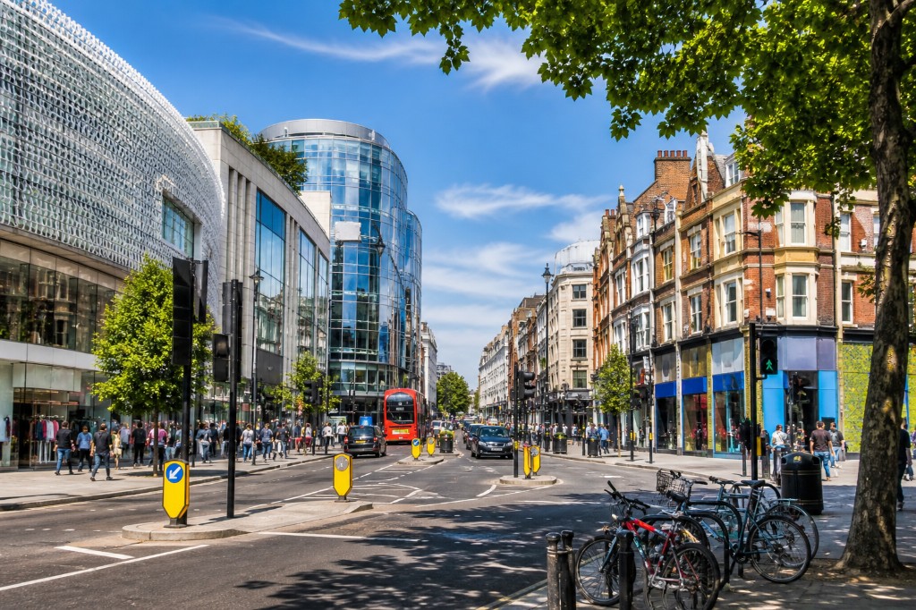 Shepherd&rsquo;s Bush: modern Westfield glass beside traditional high street, red bus, trees and busy sidewalks